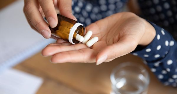 Frau, schüttet Tabletten aus einer Packung heraus.