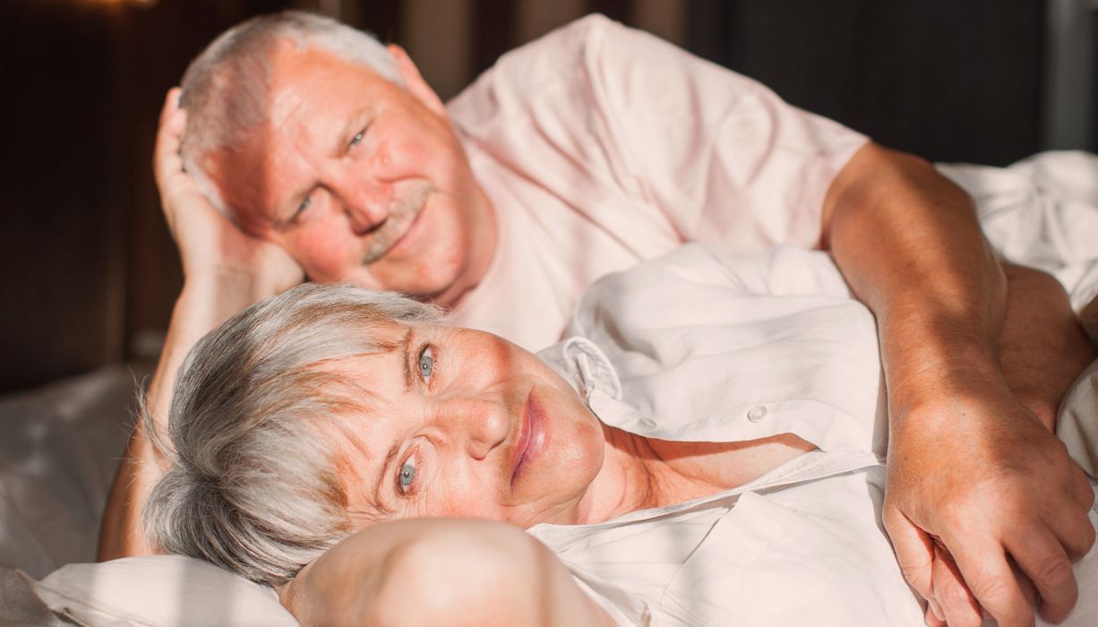 Älterer Mann und Frau, liegen zusammen im Bett.