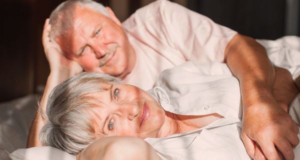 Älterer Mann und Frau, liegen zusammen im Bett.