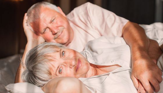 Älterer Mann und Frau, liegen zusammen im Bett.