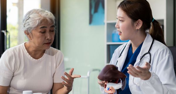 Eine Ärztin erklärt einer älteren Patienten etwas anhand eines Leber-Modells.