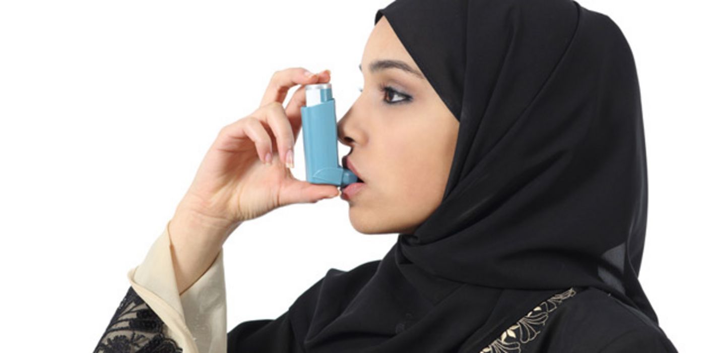 Muslimische Frau inhaliert mit einem Asthma-Spray.