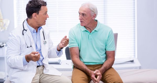 Arzt, spricht mit einem männlichen älteren Patienten.