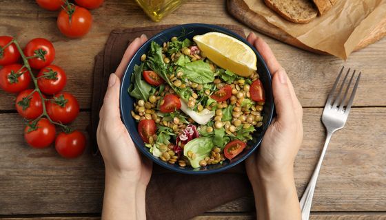 Hände umfassen eine Schüssel mit leckerem Linsensalat.