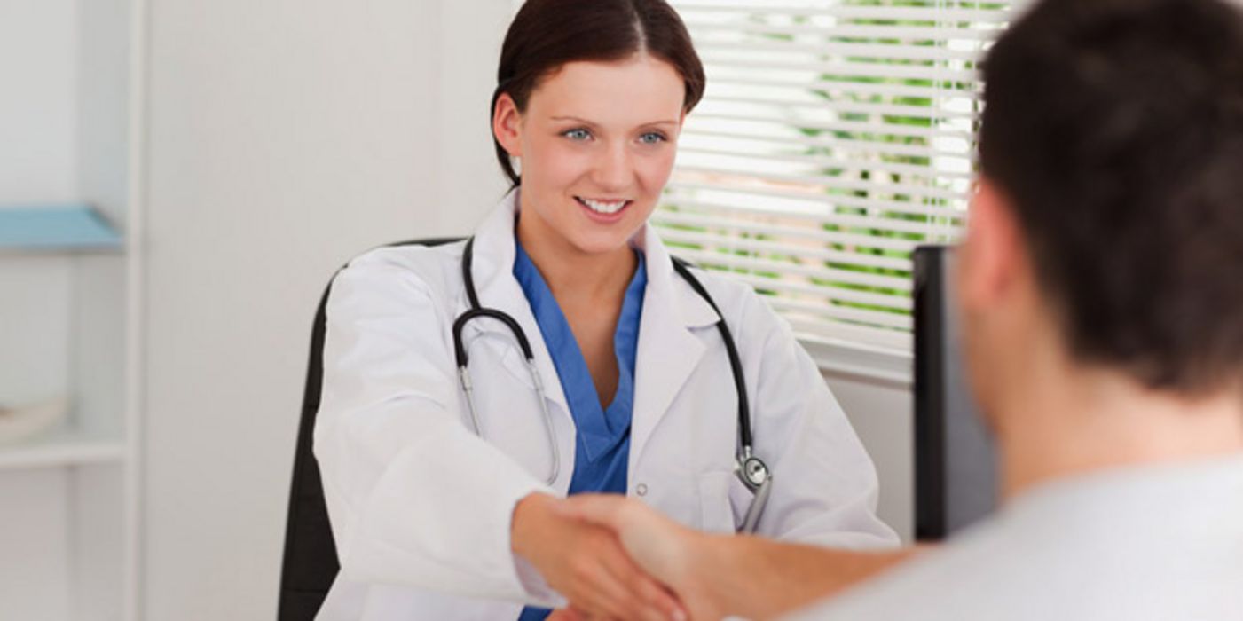 Ärztin schüttelt Patient die Hand.