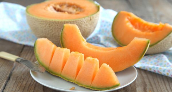 Aufgeschnittene Cantaloupe-Melone, ein Stück auf einem Löffel