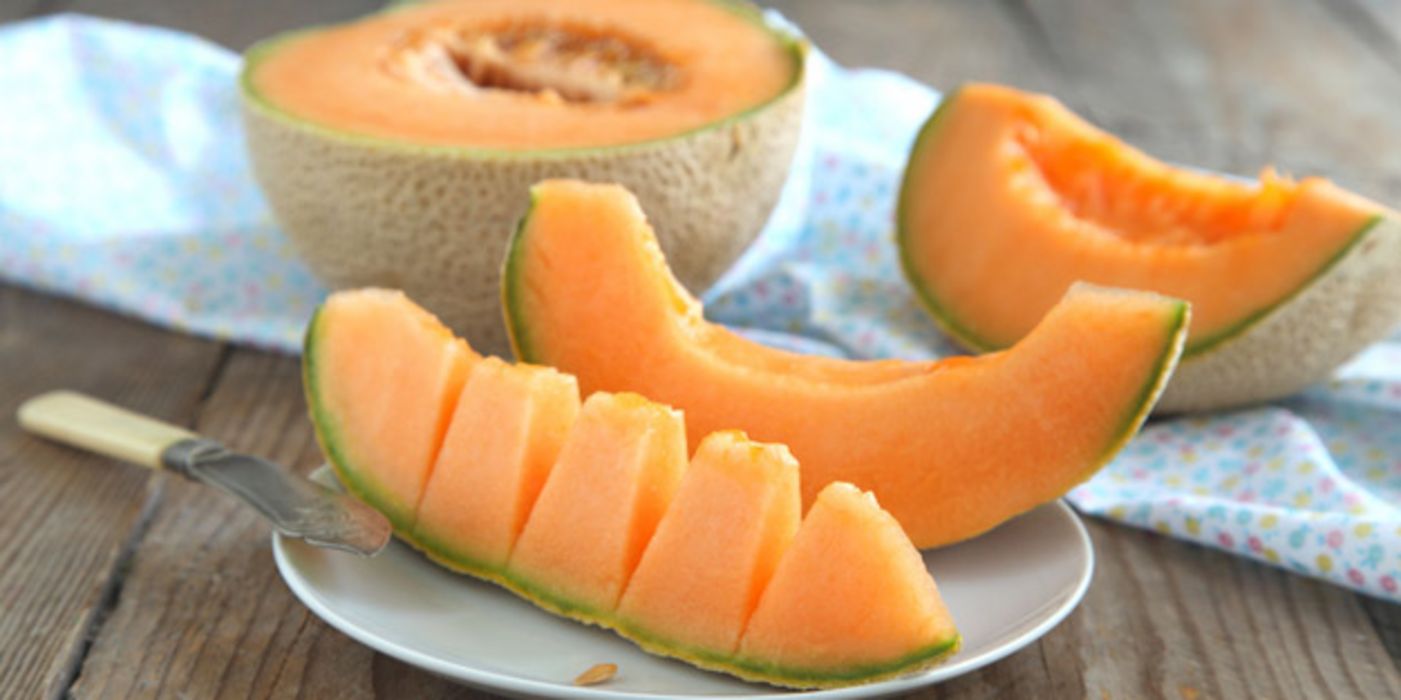 Aufgeschnittene Cantaloupe-Melone, ein Stück auf einem Löffel