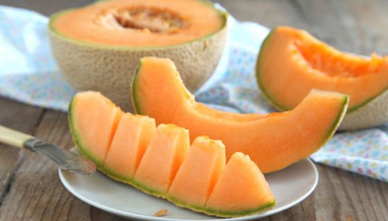 Aufgeschnittene Cantaloupe-Melone, ein Stück auf einem Löffel