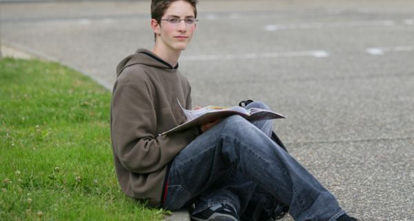 Junge sitzt auf Schulhof.