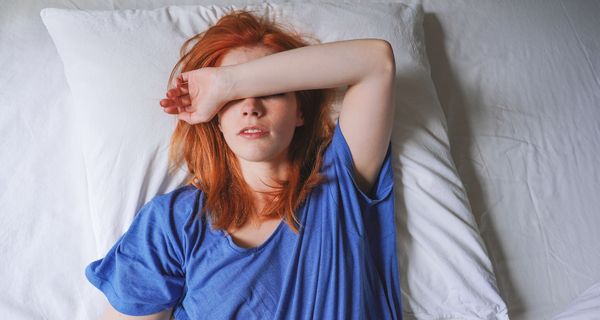 Junge Frau, liegt müde im Bett.