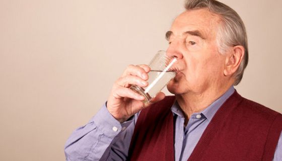 Alter Mann trinkt ein Glas Wasser