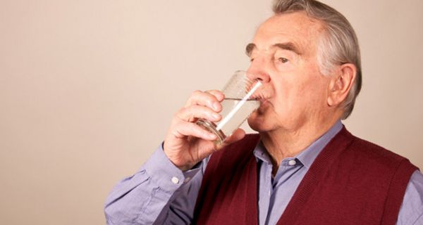 Älterer Mann trinkt ein Glas Wasser