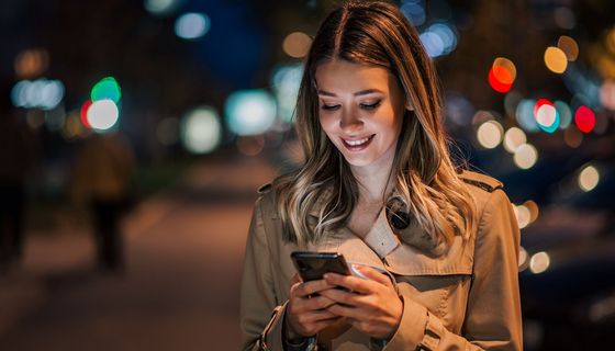 Frau mit Handy in nächtlicher Straße