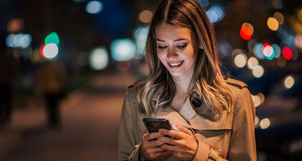 Frau mit Handy in nächtlicher Straße