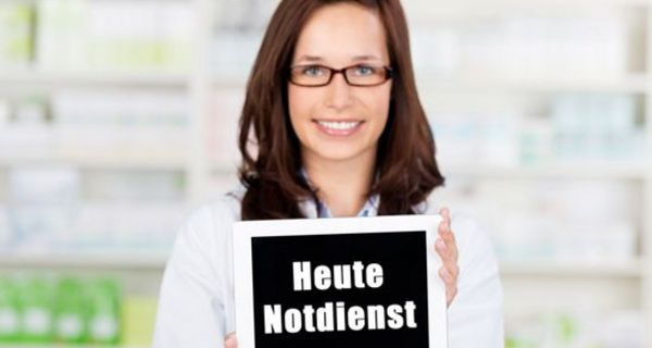 Apothekerin hält ein Schild mit der Aufschrift "Heute Notdienst" in die Kamera