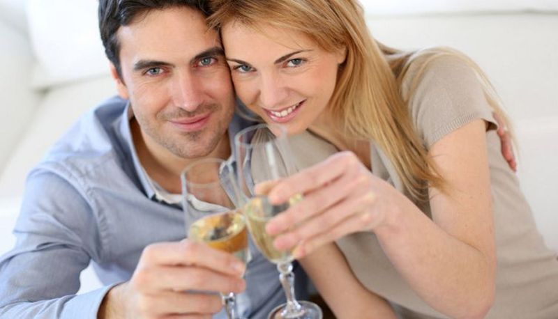 Mann und Frau in mittlerem Alter stoßen mit zwei Gläsern Sekt an