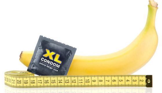 Stillleben: Banane liegend, davor Kondom in Packung, gelbes Bandmaß an Banane