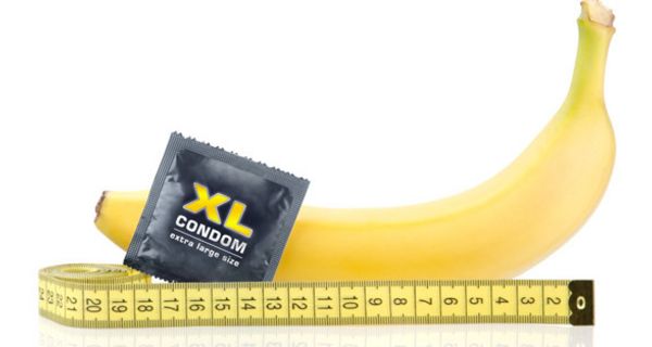 Stillleben: Banane liegend, davor Kondom in Packung, gelbes Bandmaß an Banane