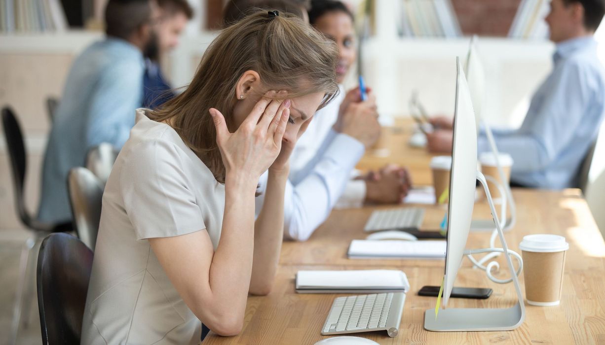 Junge Frau, sitzt müde vor ihrem Computer im Büro.