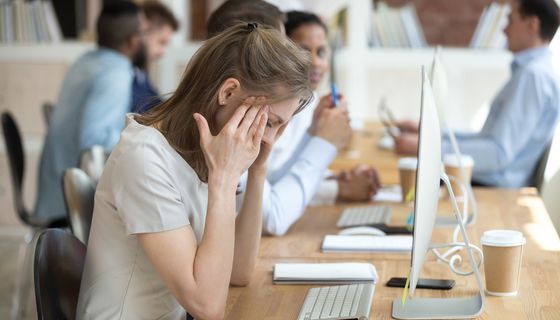 Junge Frau, sitzt müde vor ihrem Computer im Büro.
