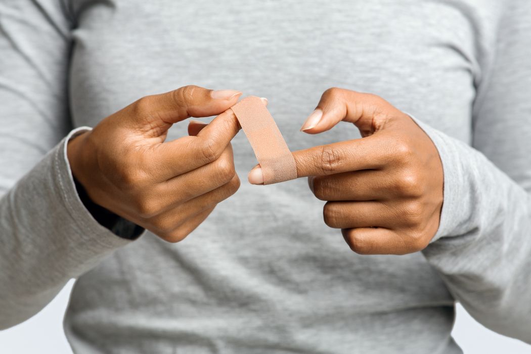 Eine Frau klebt sich ein Pflaster auf den Finger.