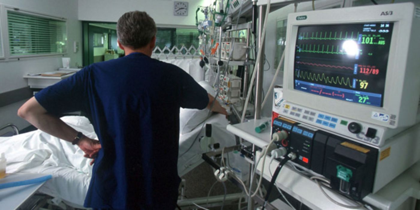 Intensivstation mit Apparaturen und Pfleger/Arzt, der mit dem Rücken zur Kamera steht
