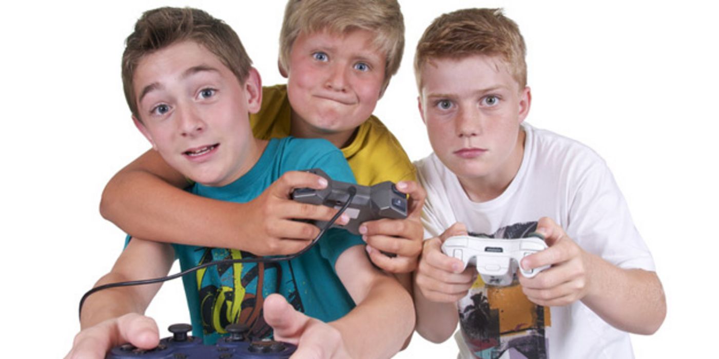 Drei Jungs mit Spielkonsolen und gebanntem Gesichtsausdruck