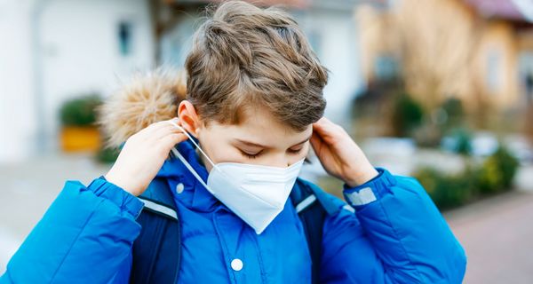 Junge, draußen im Winter, zieh sich FFP2-Maske an.