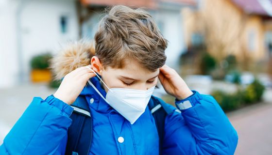 Junge, draußen im Winter, zieh sich FFP2-Maske an.