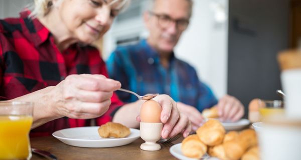 Frau, klopft auf ihr Frühstücksei mit einem Löffel.