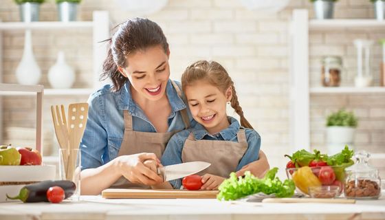 Mutter und Tochter schneiden Gemüse.