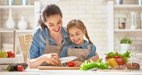 Mutter und Tochter schneiden Gemüse.