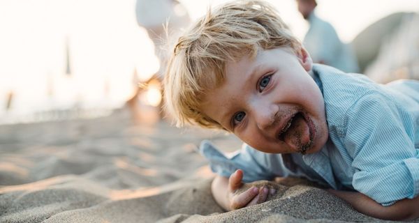 Kind, steckt sich Sand in den Mund.