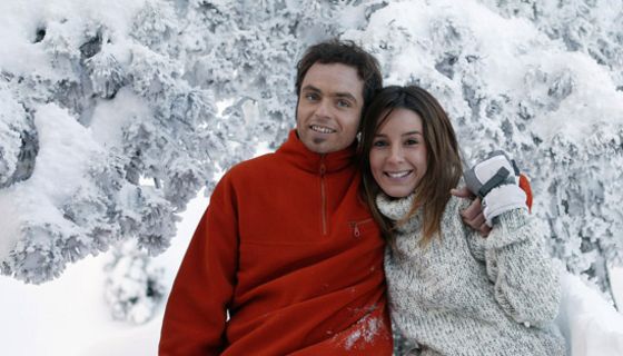 Paar steht in winterlicher Landschaft und atmet die klare Luft