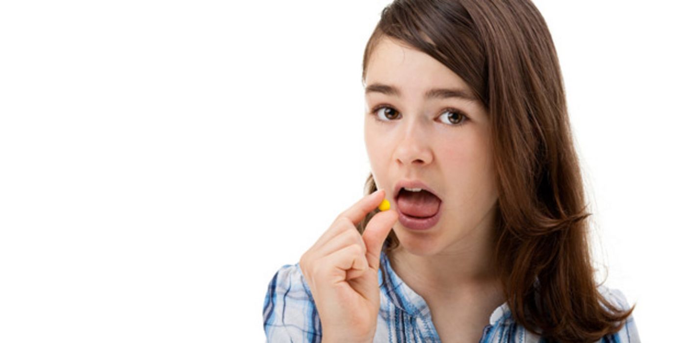 Mädchen, ca. 11 bis 13 Jahre alt, beim Einnehmen einer Tablette