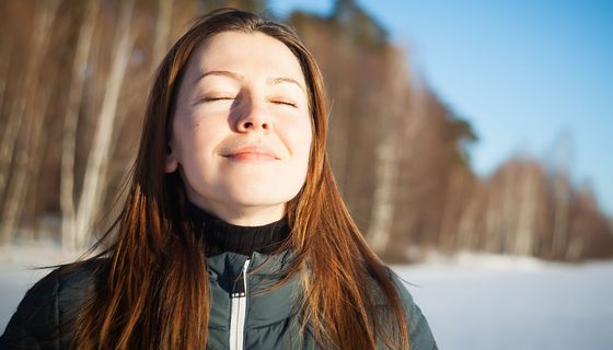 Junge Frau, streckt ihr Gesicht in die Sonne. 