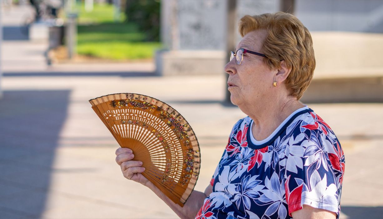 Frau, fächert sich draußen Luft zu.