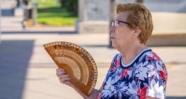 Frau, fächert sich draußen Luft zu.