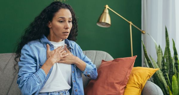 Frau ringt um Luft und presst sich beide Hände auf das Brustbein.