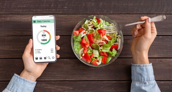 Smartphone mit Abnehm-App neben einer Schüssel Salat.