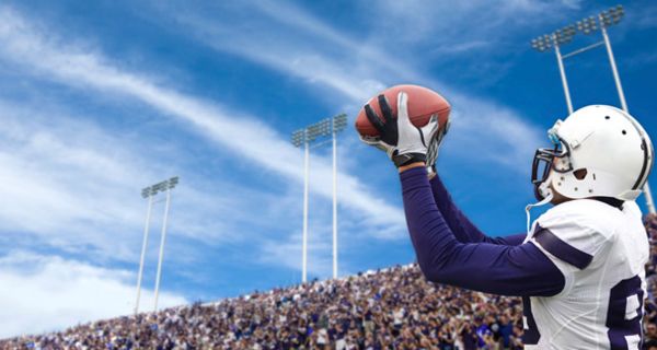 American Football-Spieler im Stadion fängt einen Football