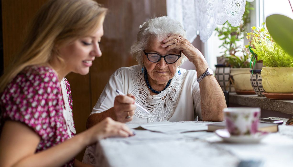 Ältere Frau, sitzt mit einer jungen Frau am Esstisch.