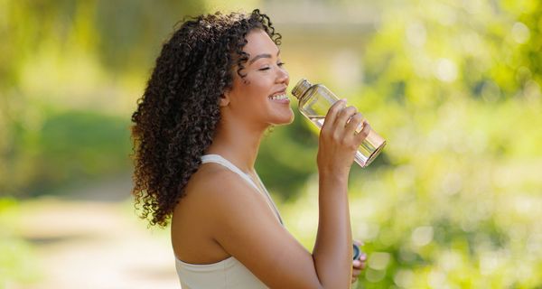 Junge Frau trinkt Wasser aus einer Flasche.