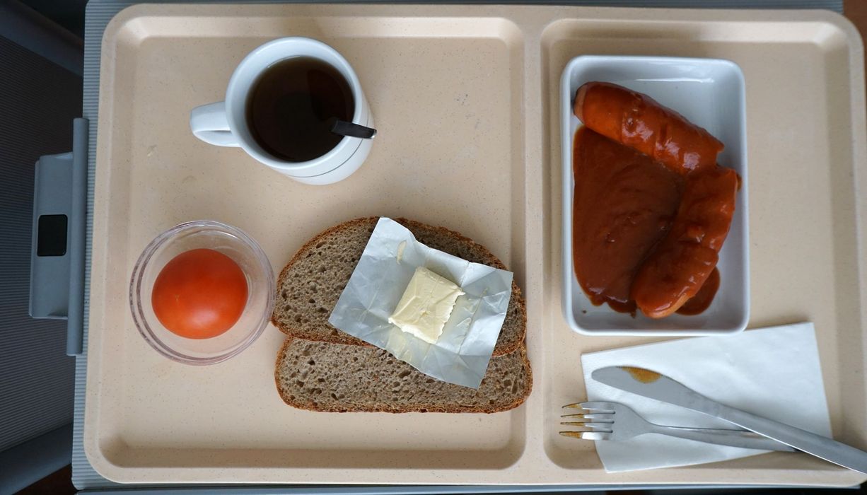 Tablett mit Klinikessen: Wurst, Brot, Butter und eine Tomate.