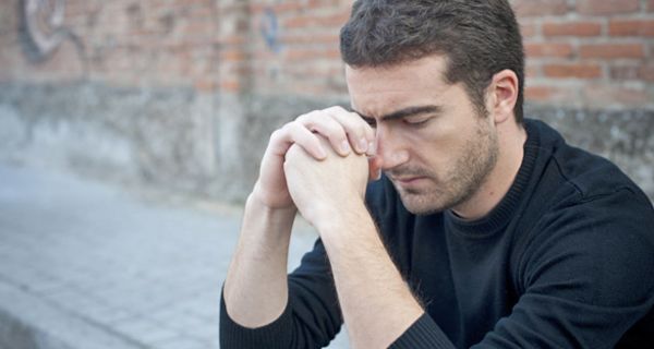 Depressiver Mann sitzt auf einem Bordstein