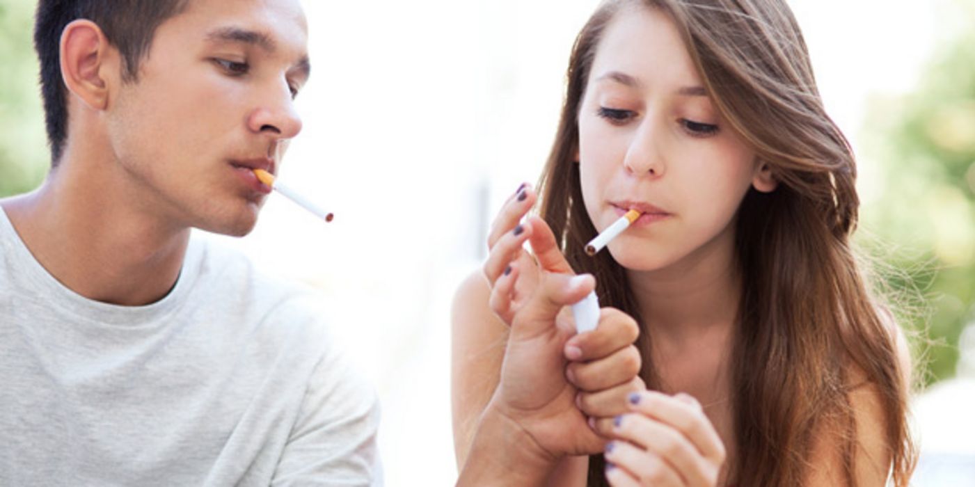 Teenager, ca. 16 Jahre alt, beide mit Zigaretten im Mund, er gibt ihr Feuer
