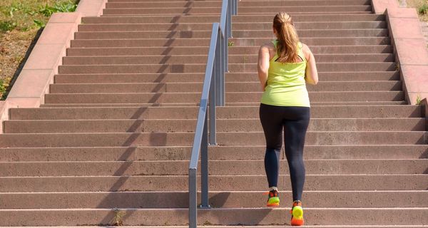 Junge Frau, joggt eine Treppe hoch.