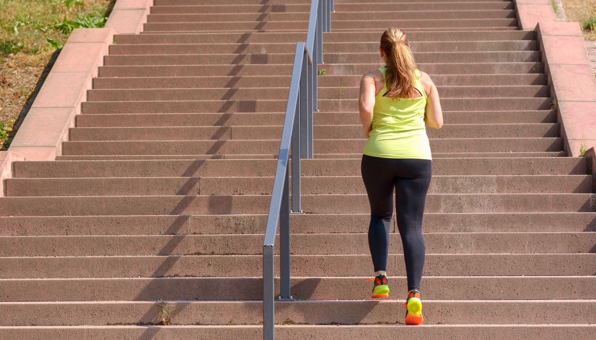 Junge Frau, joggt eine Treppe hoch.