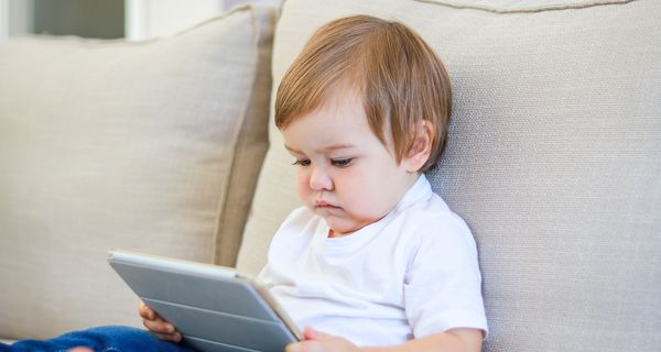 Baby mit einem Tablet auf dem Schoß.