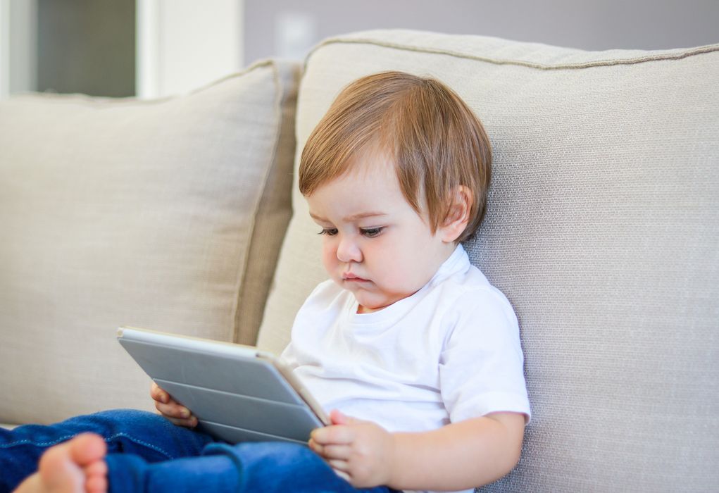 Baby mit einem Tablet auf dem Schoß.